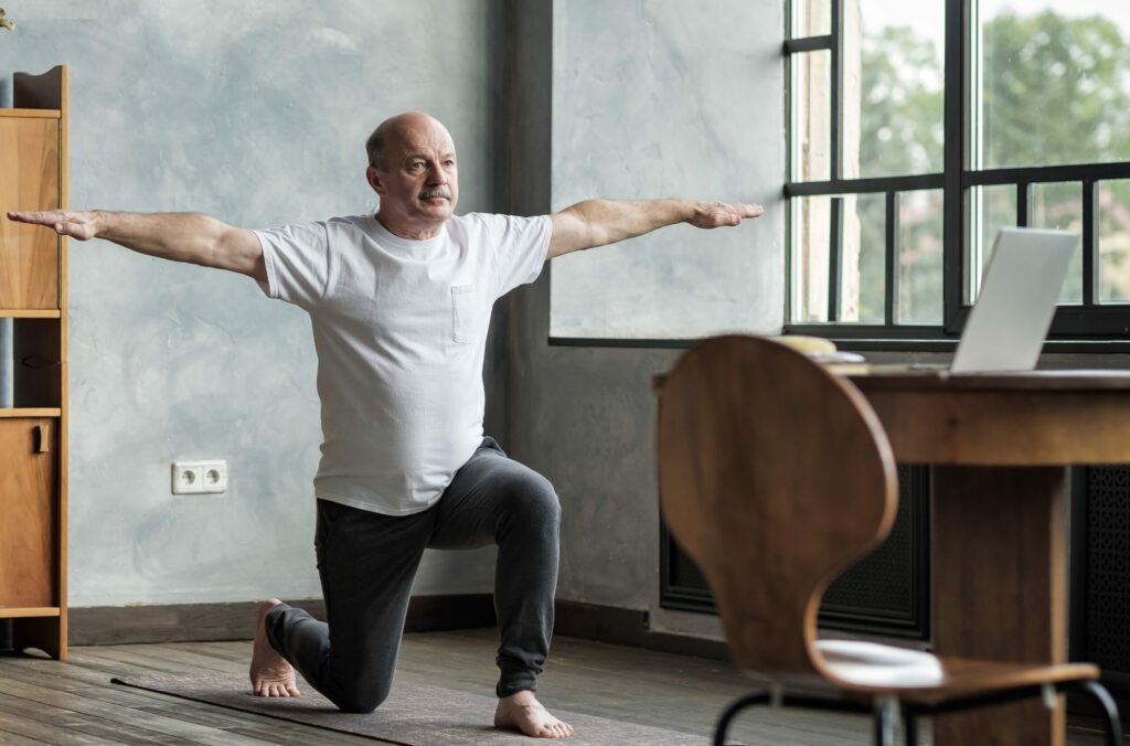 Senior Hispanic Man Standing In Warrior Yoga Pose Variation