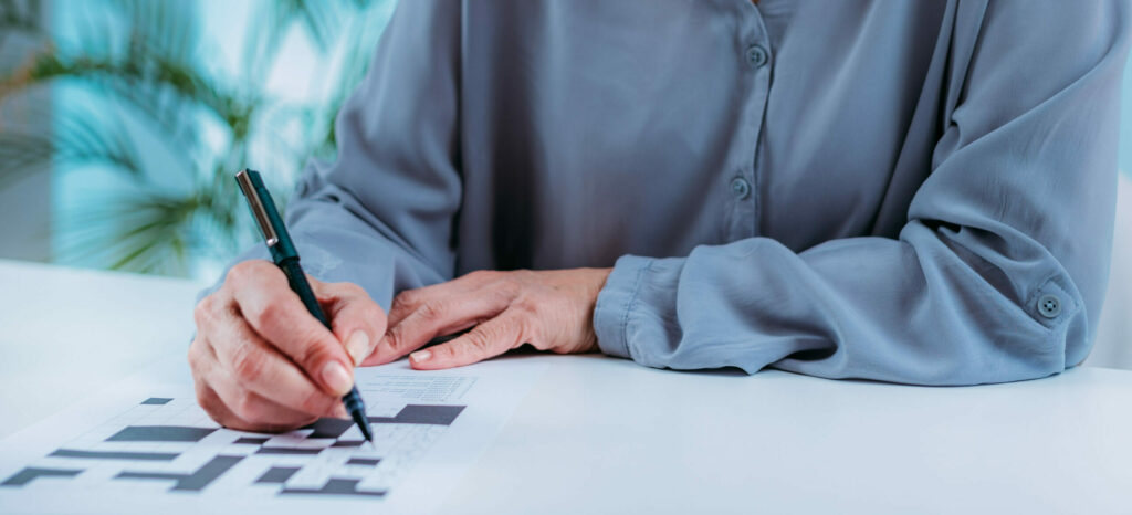 Cognitive Training For The Elderly. Senior Woman Solving Crossword Puzzles.