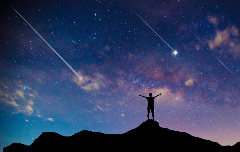 Amazing Beautiful Night Sky And Stars With Meteor Or Shooting Star As Background.Traveler Man Silhouette Stand Top Mountain.