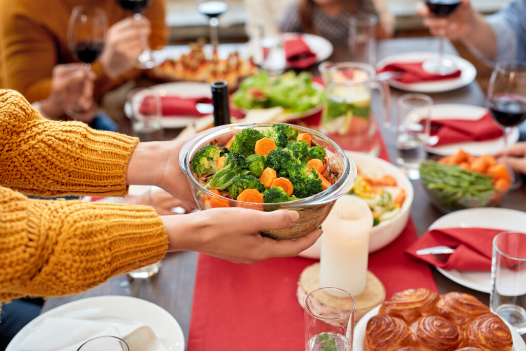 Woman Holding Bowl Full Vegetables Over Served Dinner Table