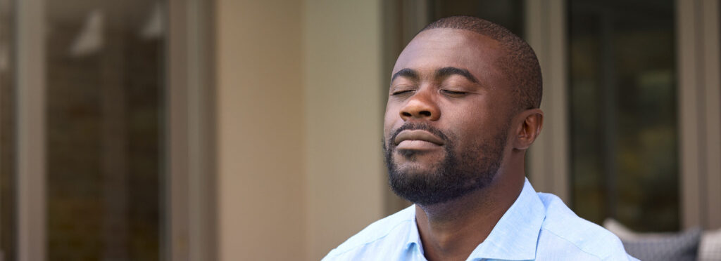 Man At Home Sitting On Deck Closing Eyes And Breathing Deeply Enjoying Peace And Calm