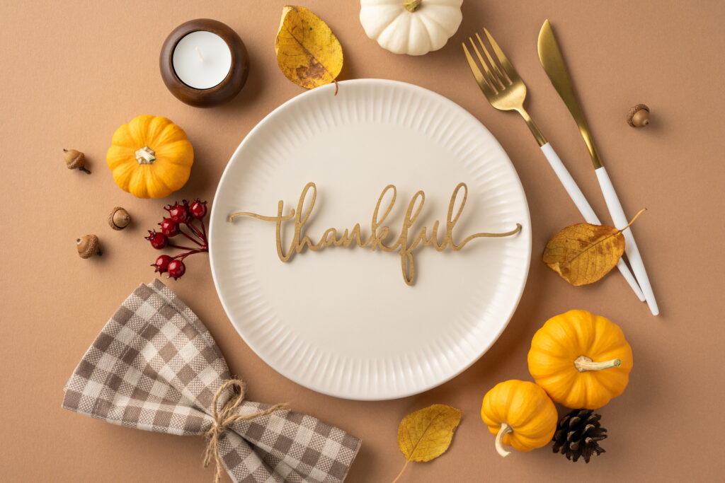 A Thanksgiving Theme Table Setting Featuring Small Pumpkins, Thankful Message On A Plate, And Autumn Decor Elements