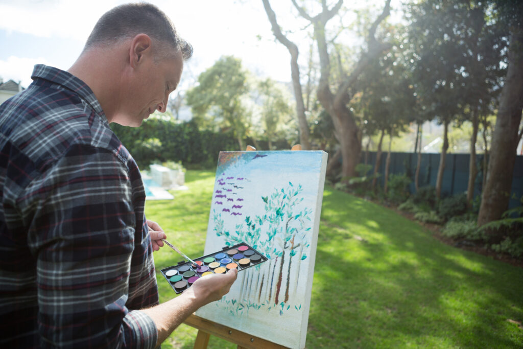 Man Painting On Canvas In Garden