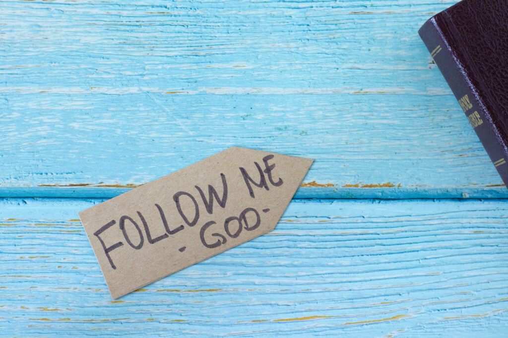Follow Me, God, Handwritten Quote On Paper Arrow And Holy Bible Book On Wooden Background, Top View